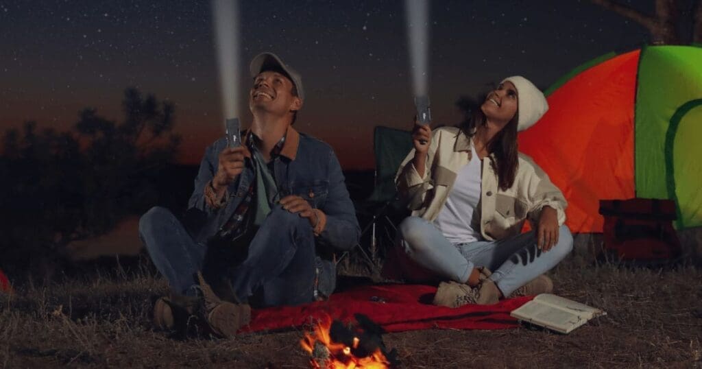 Essential Camping Gear, two campers using flashlights at night.